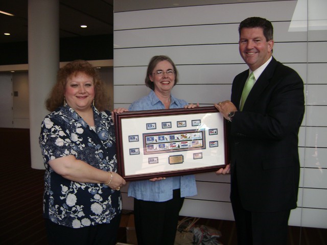 Choral director Cynthia Pratt and President Eileen Jacobs receive a complete set of first day issue commemorative stamps of Flags of our Nation from Deputy Postmaster General Patrick Donahoe at the American Philatelic Society Stamp Show, August 6, 2009 at the David Lawrence Convention Center, Pittsburgh, Pa. The Harmony Singers performed at the opening ceremonies.